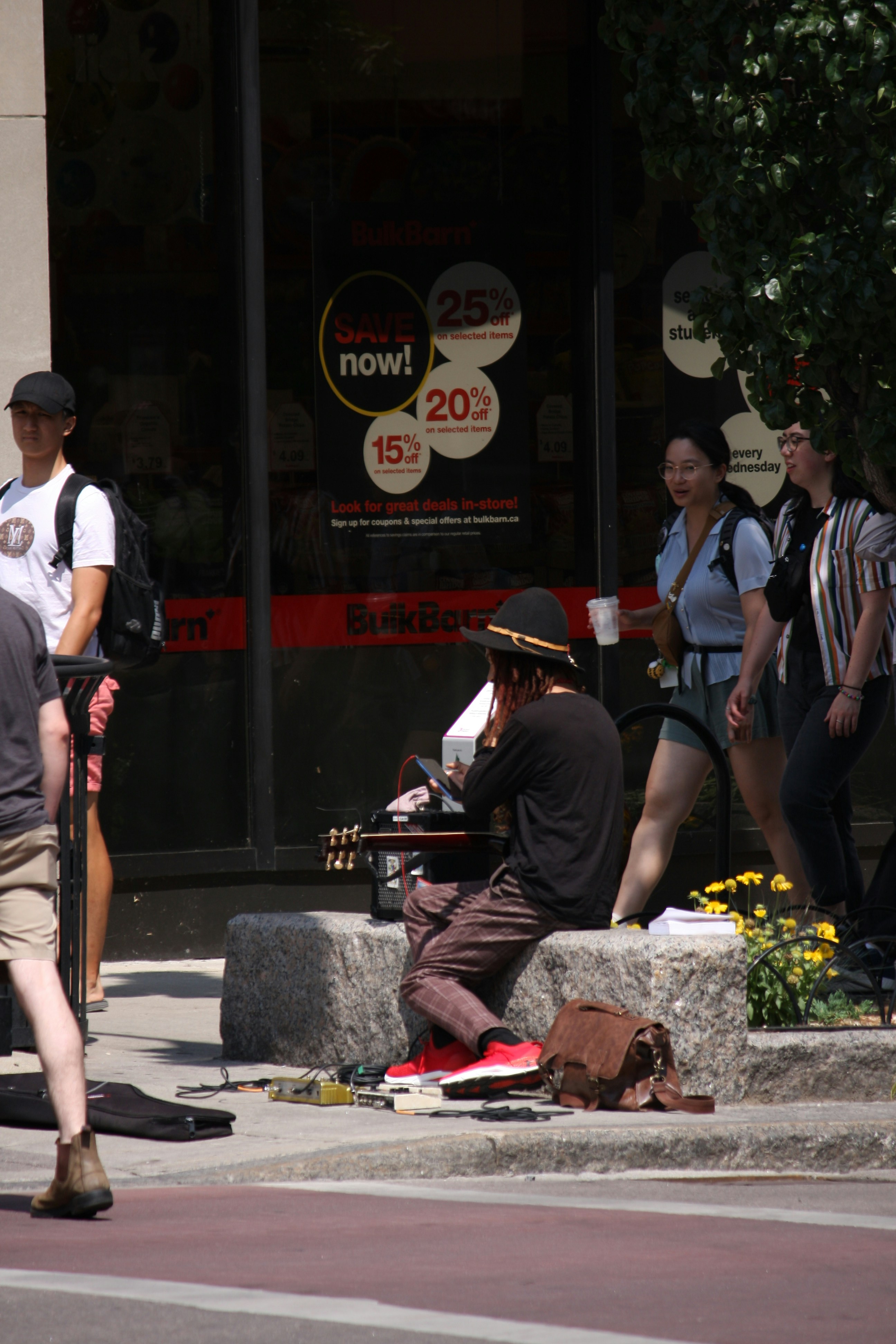 A group of people walking down a street next to a tall building