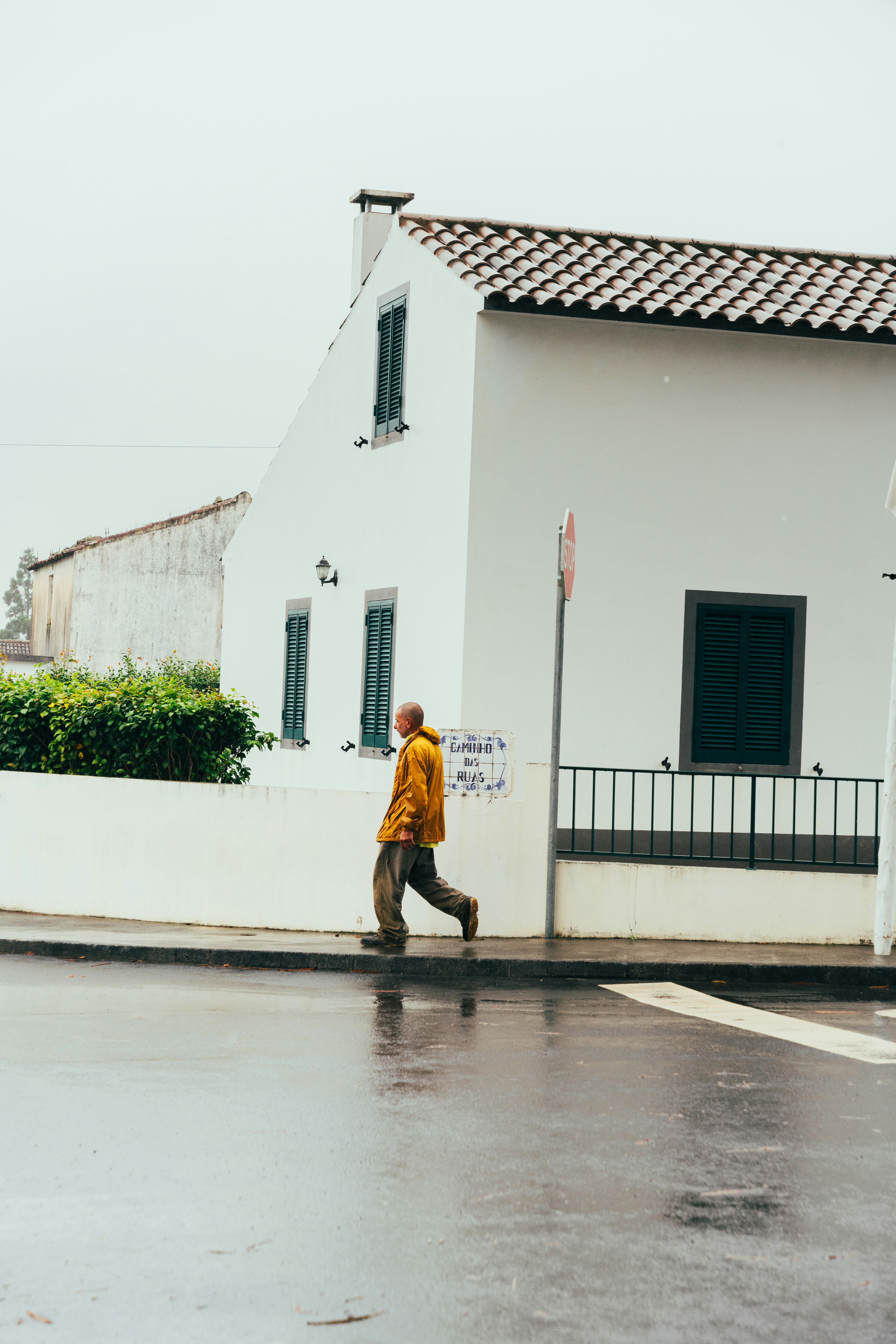 A man walking down a street next to a white building