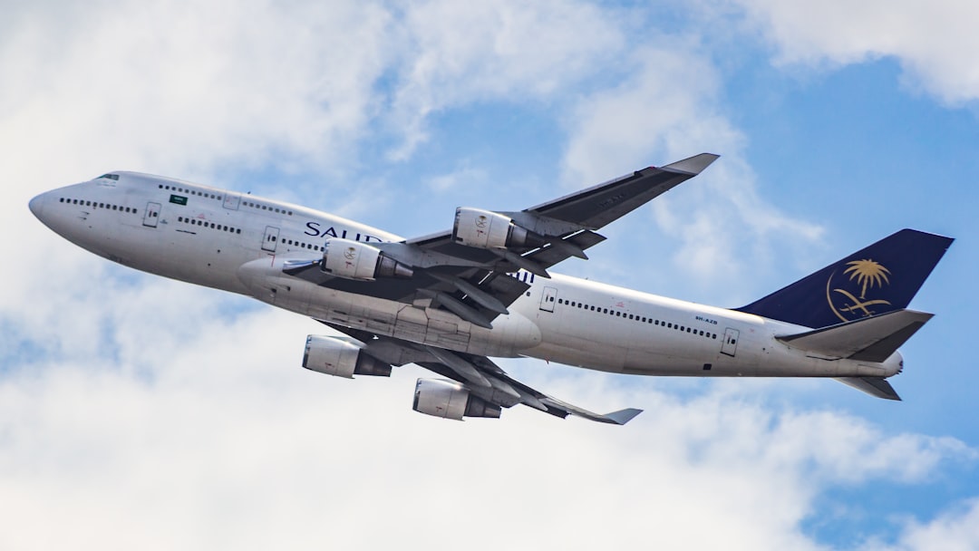 A large jetliner flying through a cloudy blue sky, Saudia Boeing 747-400 departing from Dhaka Airport to Jeddah!