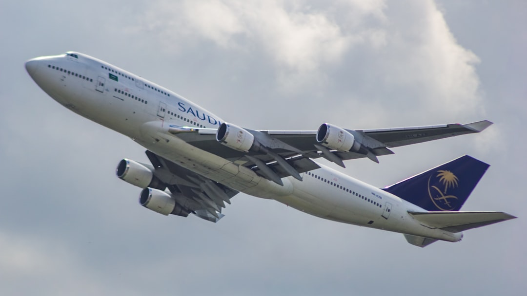A large jetliner flying through a cloudy sky, Saudia Boeing 747-400 departing from Dhaka Airport to Jeddah!