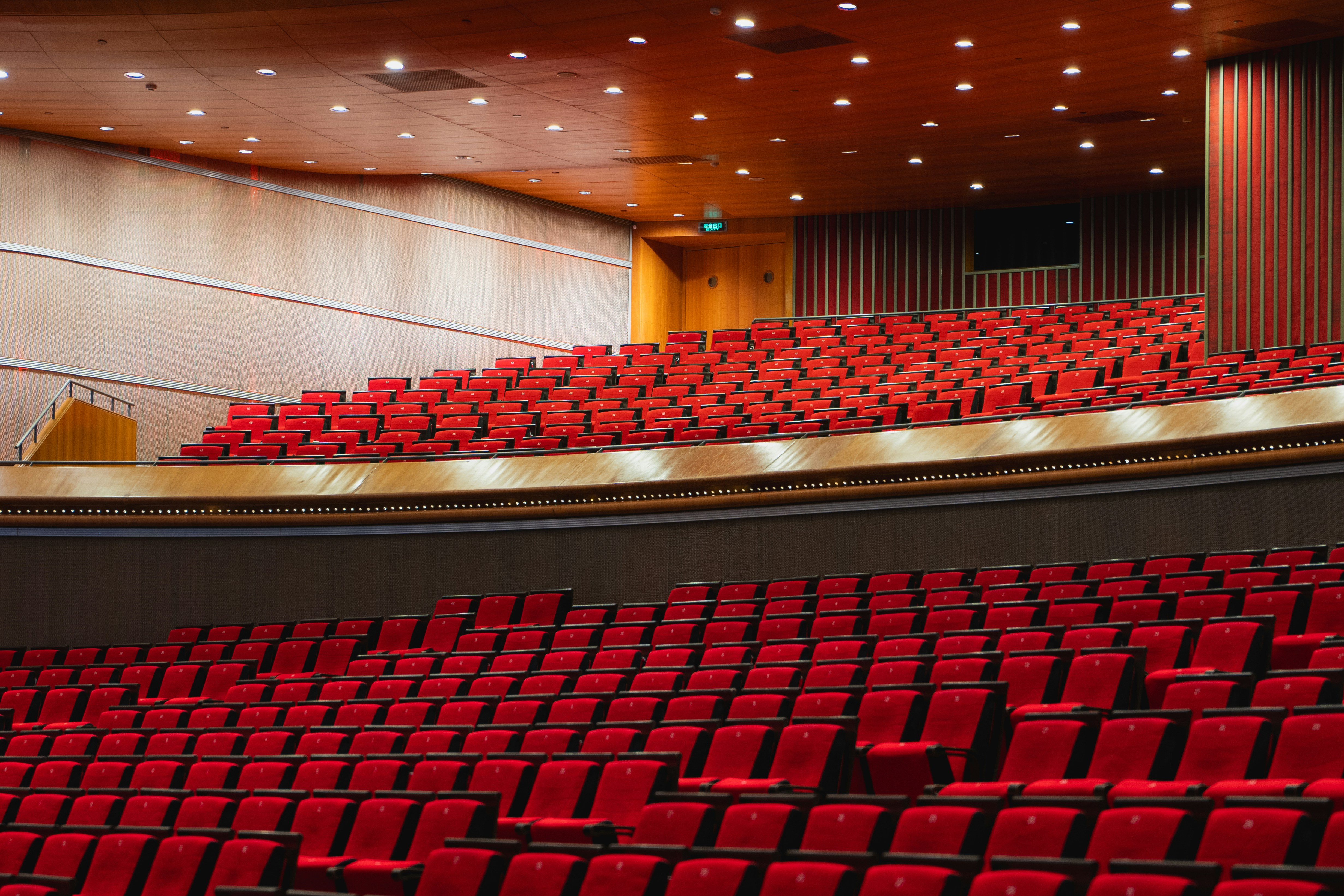 A large auditorium filled with red seats and a projector screen