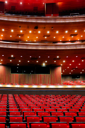 An empty auditorium with red seats and a stage
