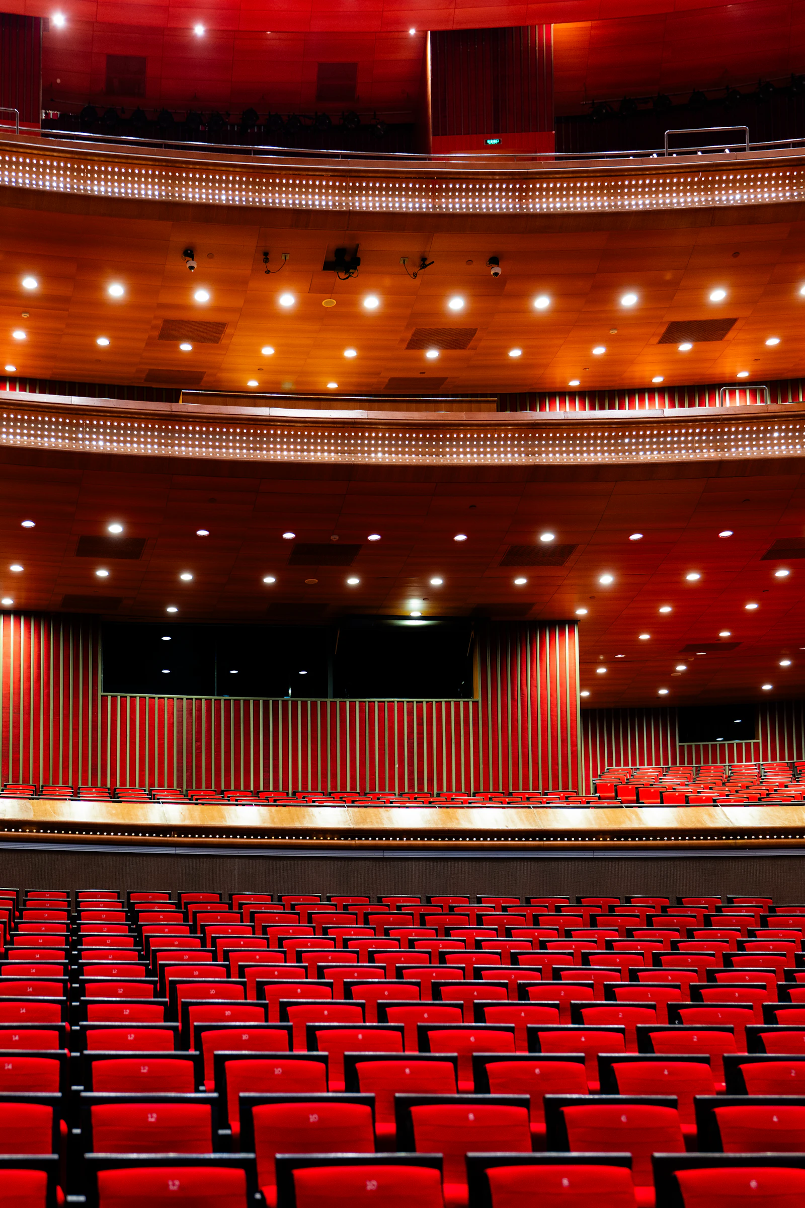 An auditorium with red seats facing a stage, set up for a conference
