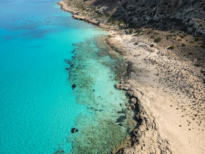 An aerial view of a beach with clear blue water