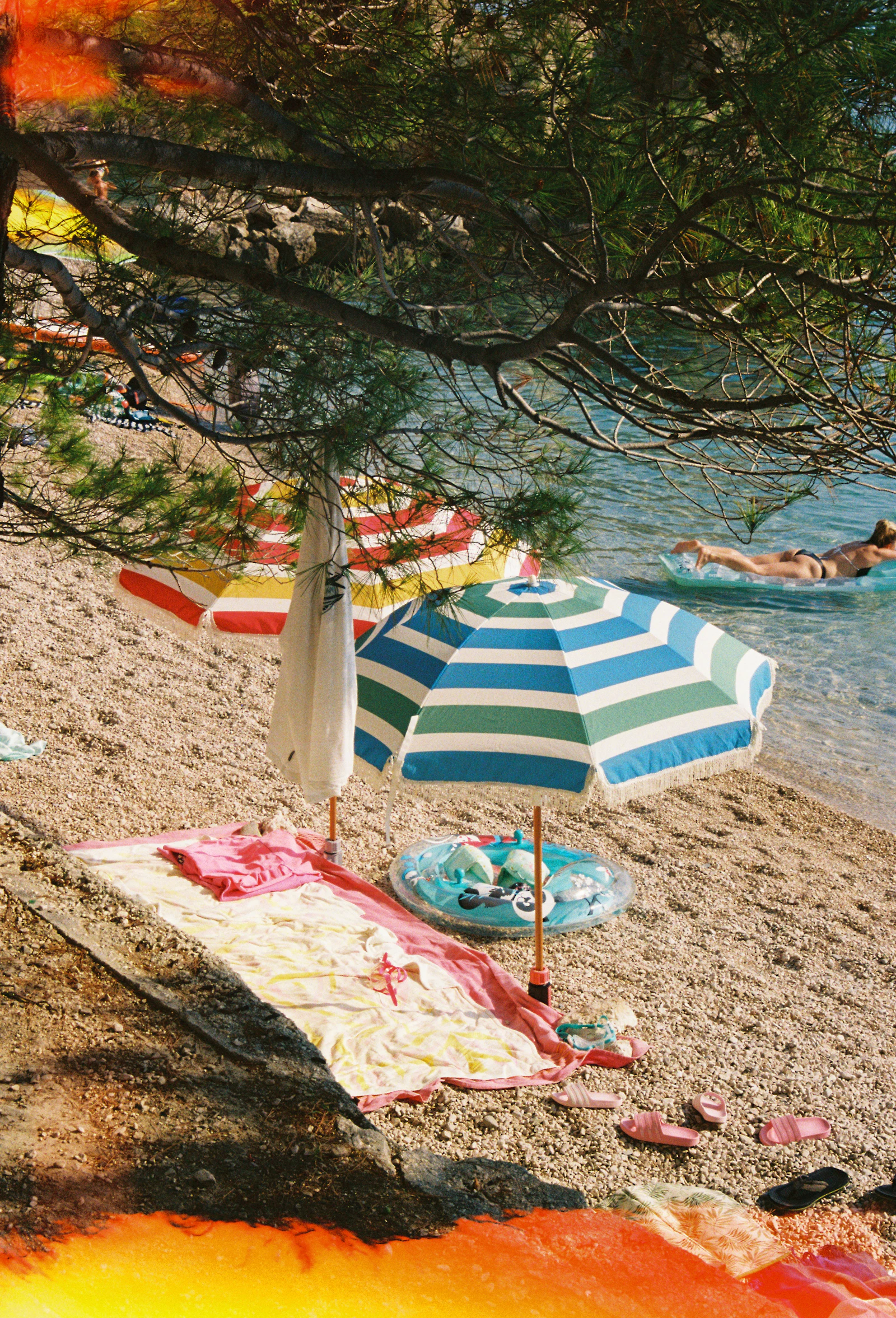 Bunte Sonnenschirme und Strandtuch an einer Bucht