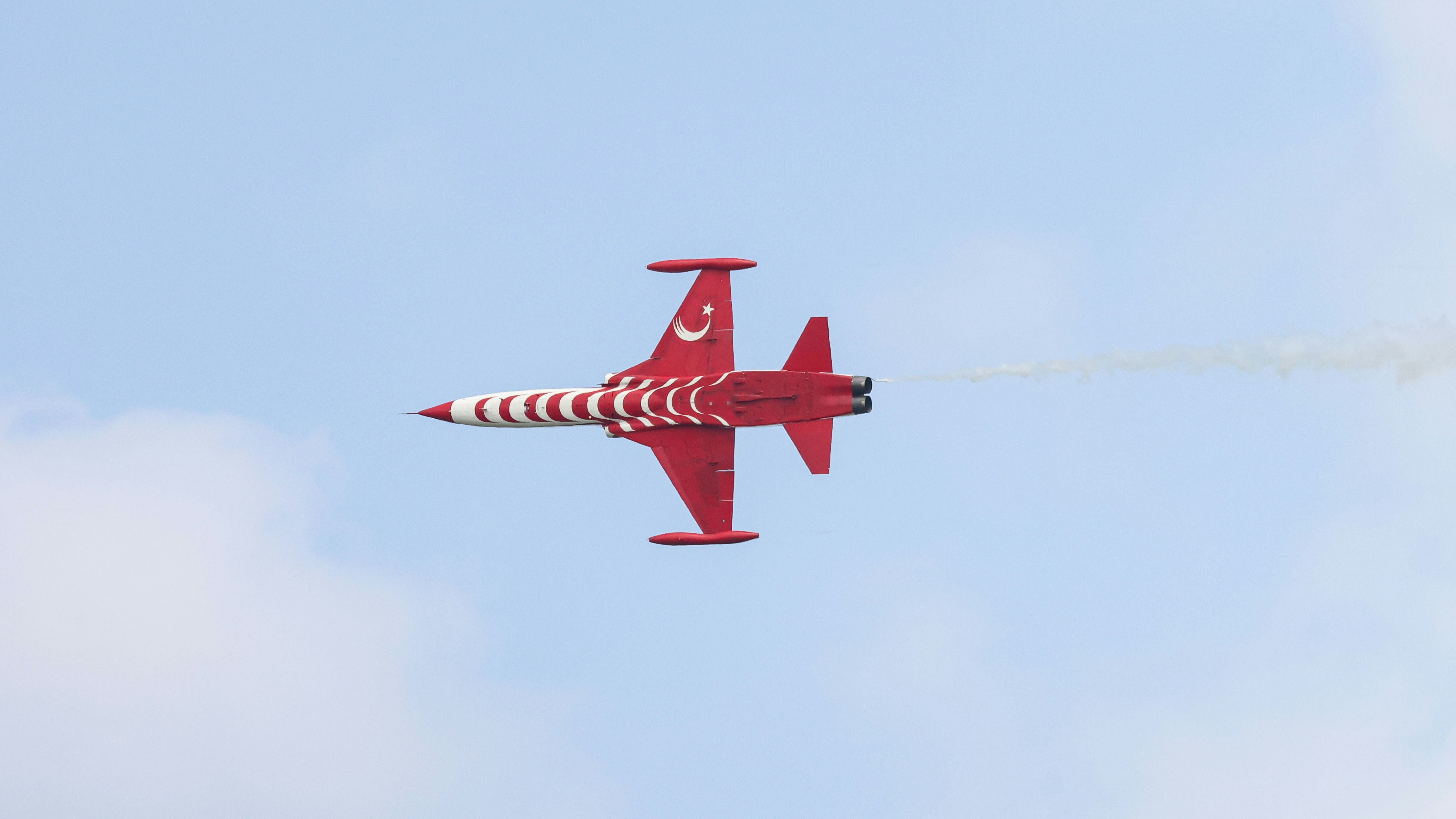 A red and white plane flying in the sky