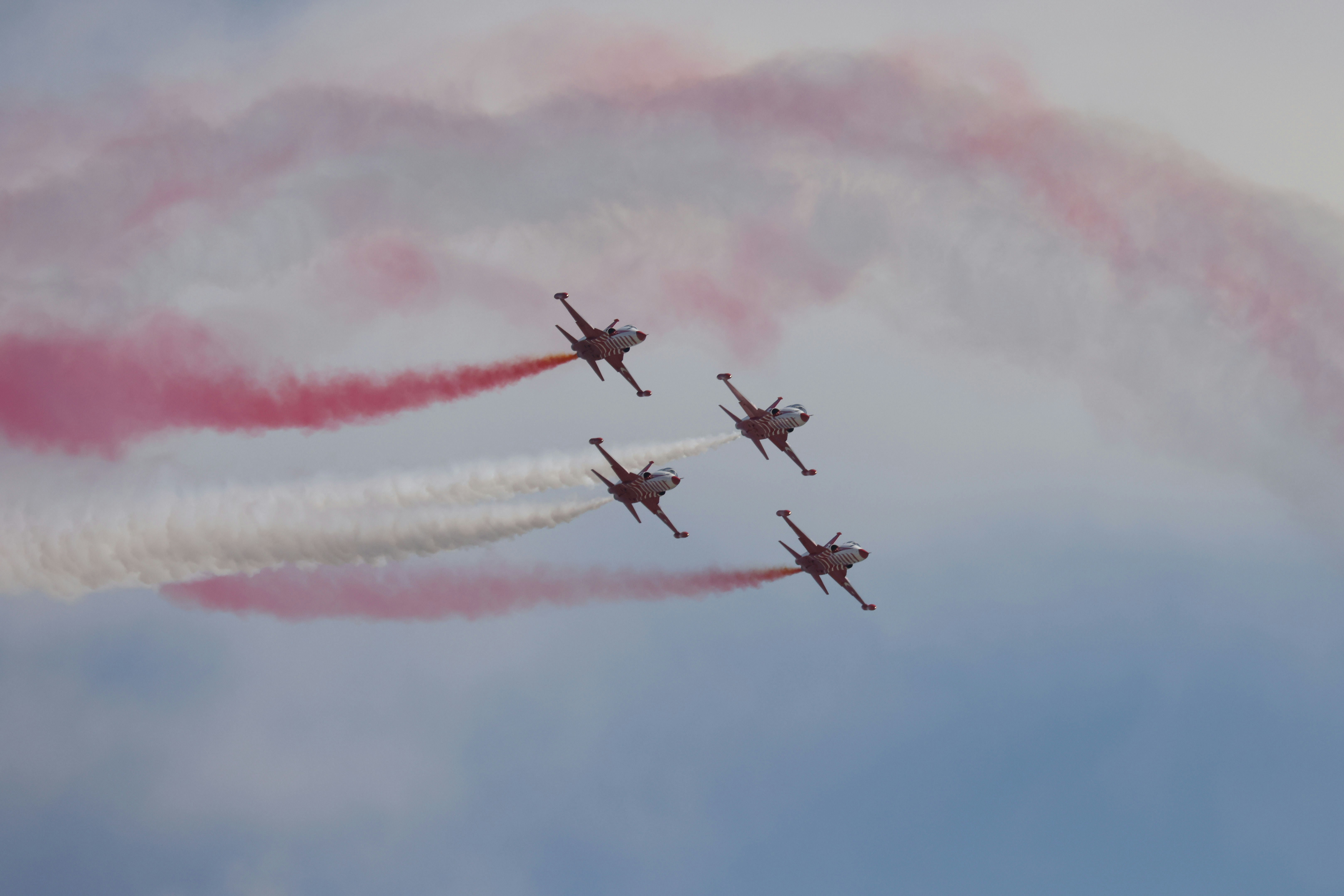 A group of jets flying through a cloudy sky, An impressive display by the Turkish Stars, featuring jets trailing red and white smoke as they perform an aerial maneuver. The photo captures the elegance and coordination of the team against a backdrop of clouds.