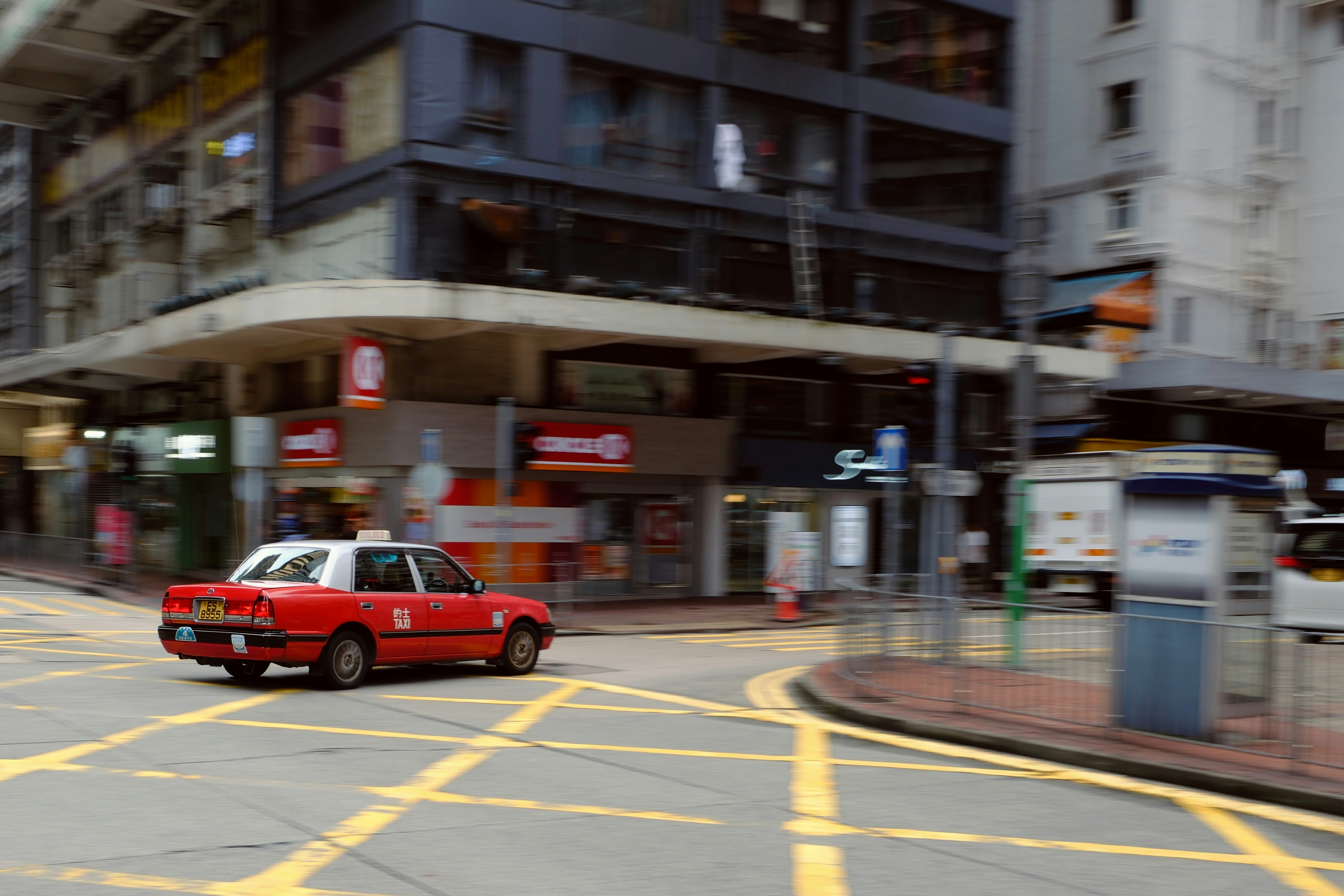 A red car driving down a street next to tall buildings photo – Free ...