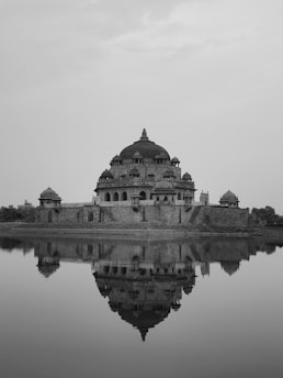 A black and white photo of a building in the middle of a body of water