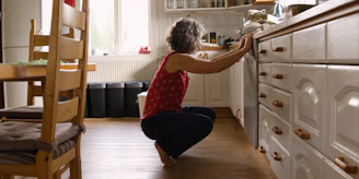 A woman kneeling on the floor in a kitchen