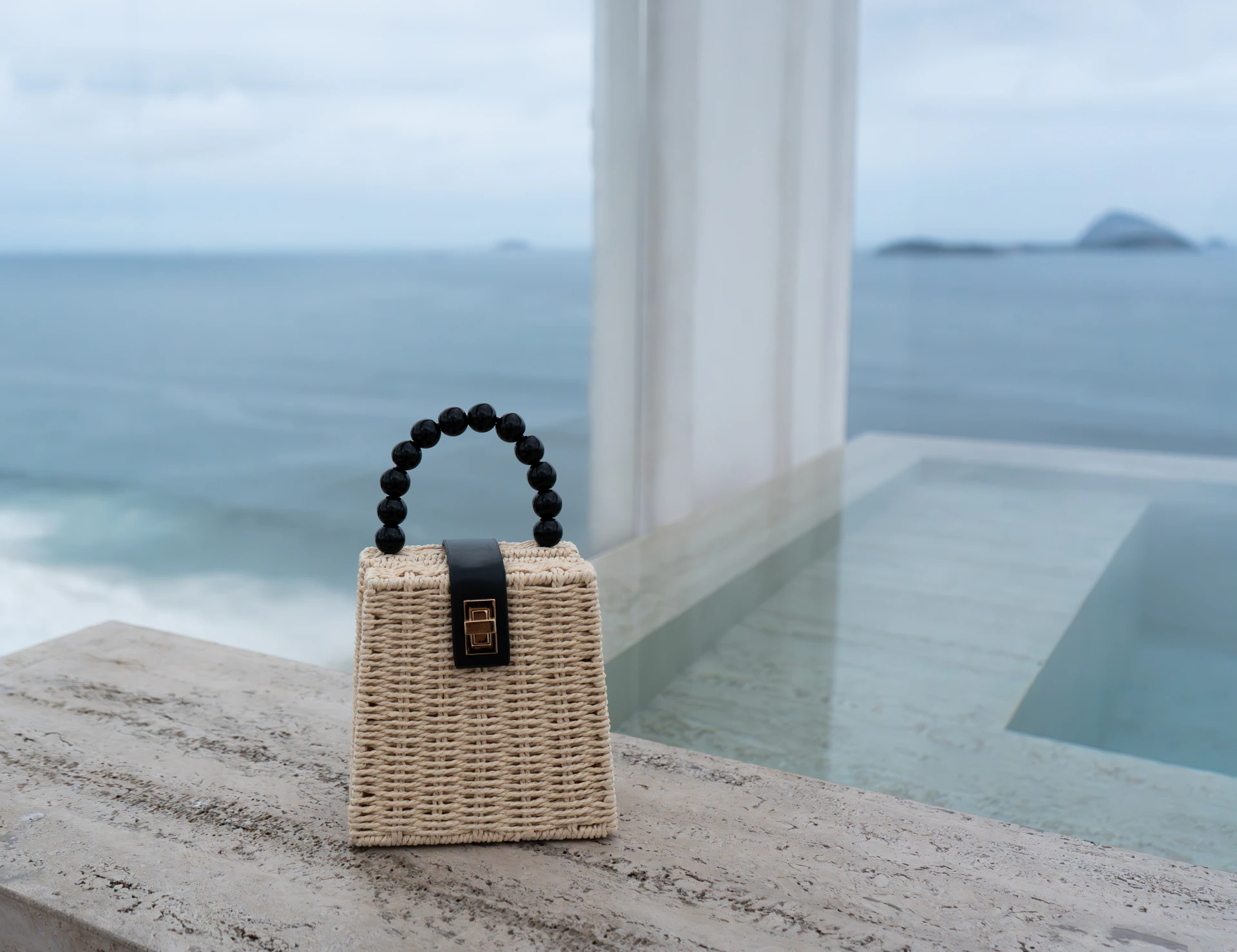 A handbag sitting on a ledge next to a body of water