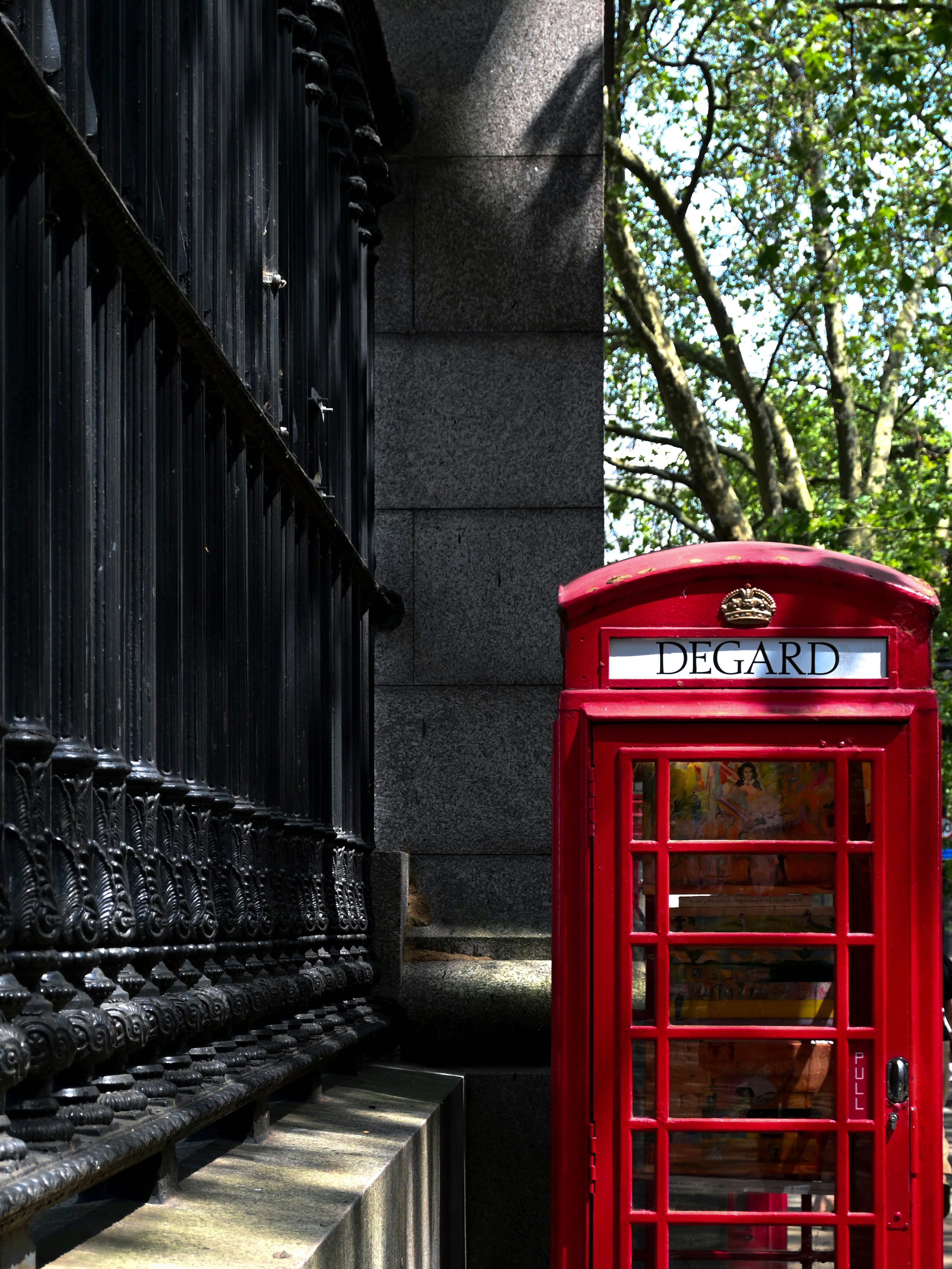A red phone booth sitting on the side of a building
