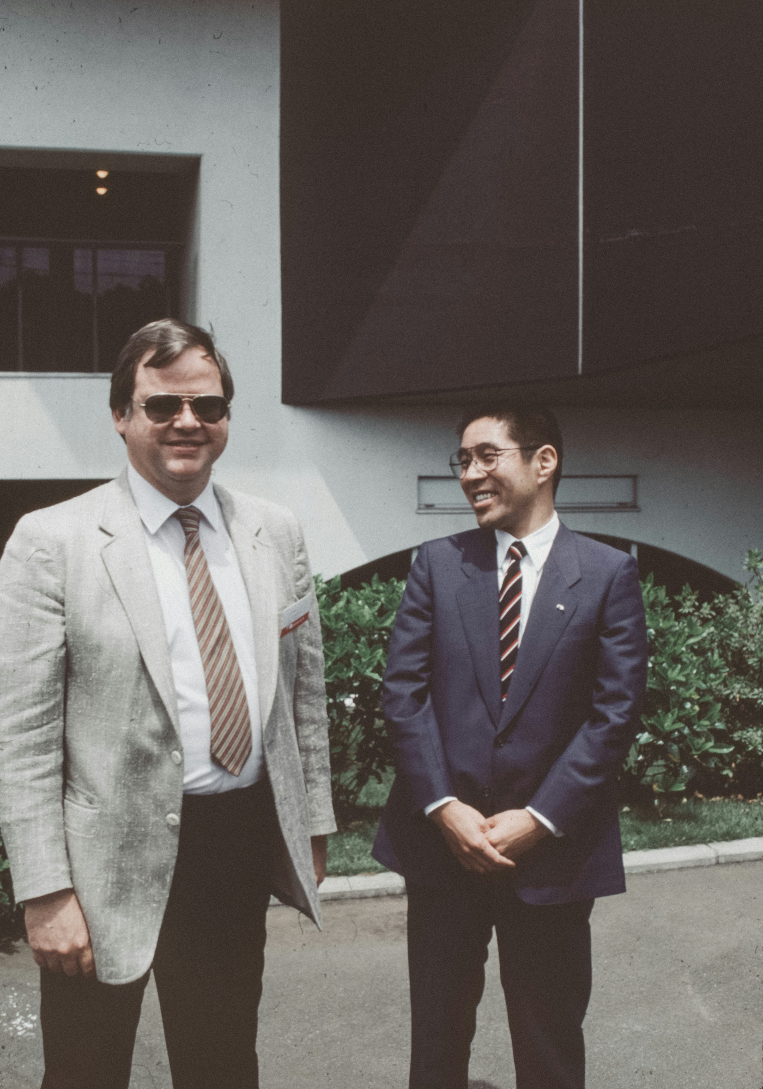 Two men standing next to each other in front of a building photo – Free ...