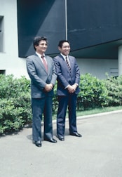 Two men standing next to each other in front of a building