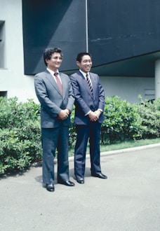 Two men standing next to each other in front of a building
