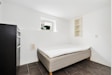 A room with a bed and a refrigerator
