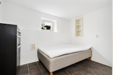 A room with a bed and a refrigerator