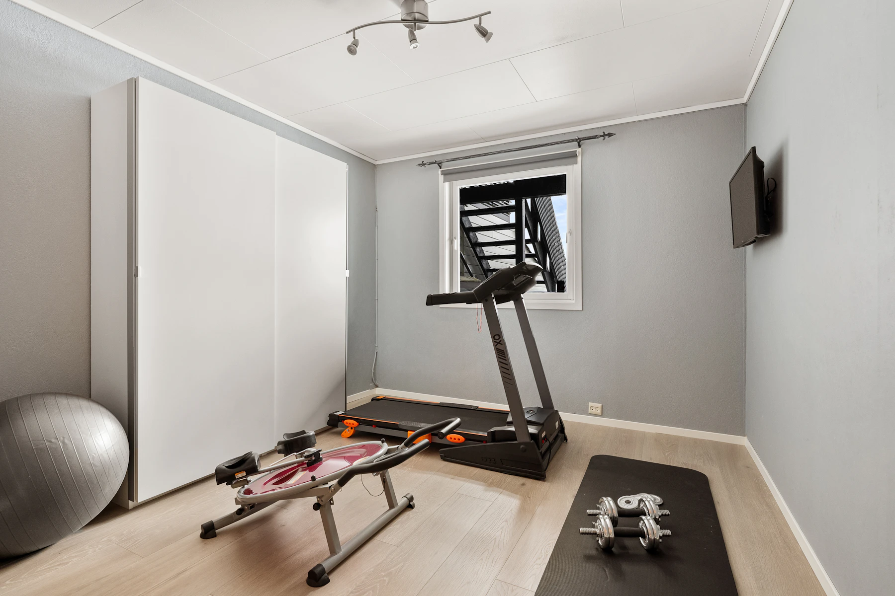 A bright home fitness space with a treadmill and desk