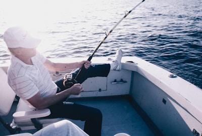 A man is fishing on a boat in the water