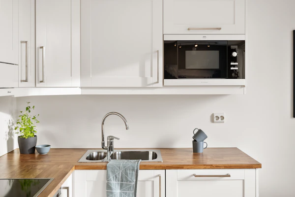 A kitchen with white cabinets and a wooden counter