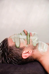A man with cucumber on his face laying on a pillow