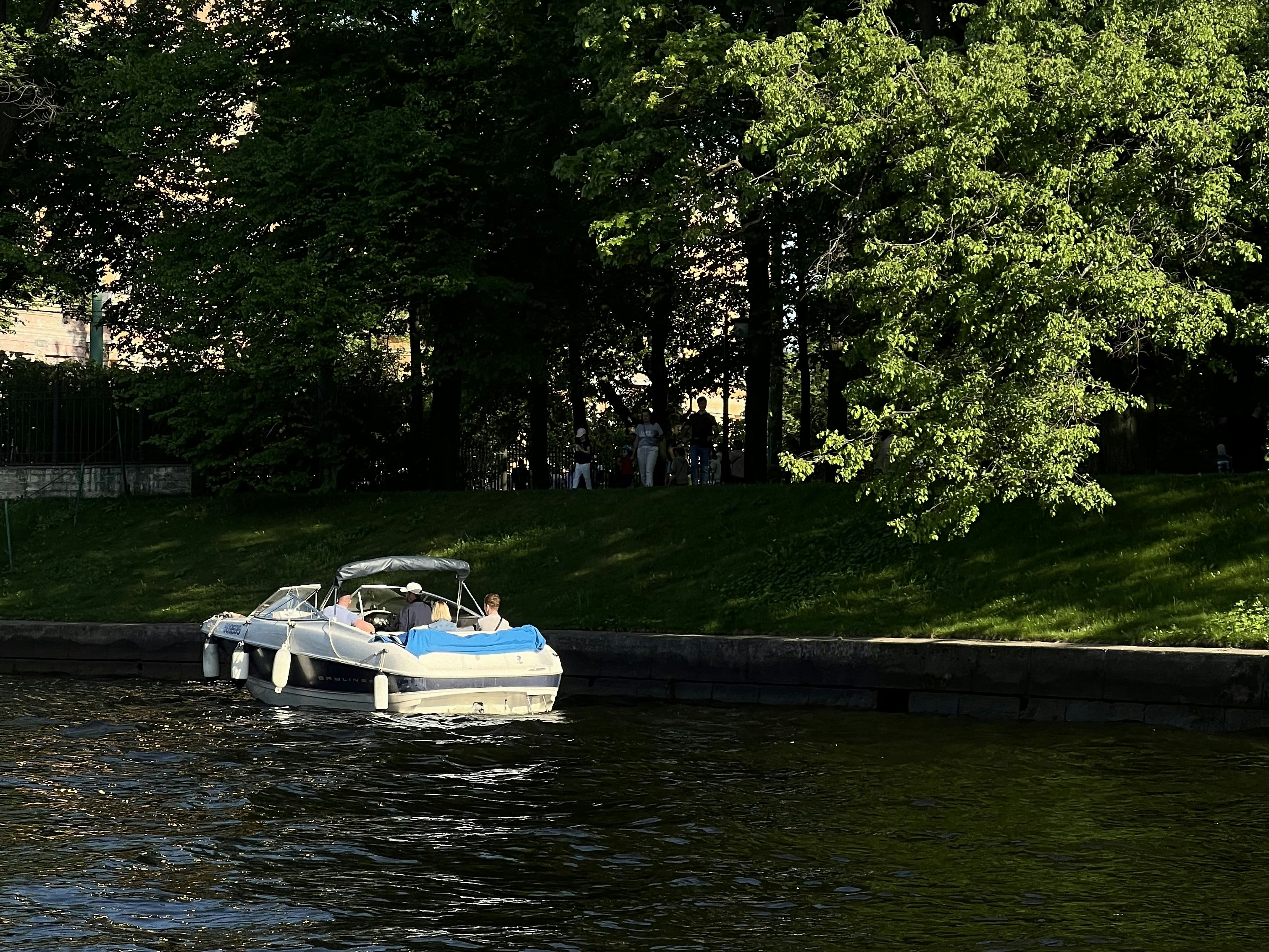 A couple of boats floating down a river next to a lush green park
