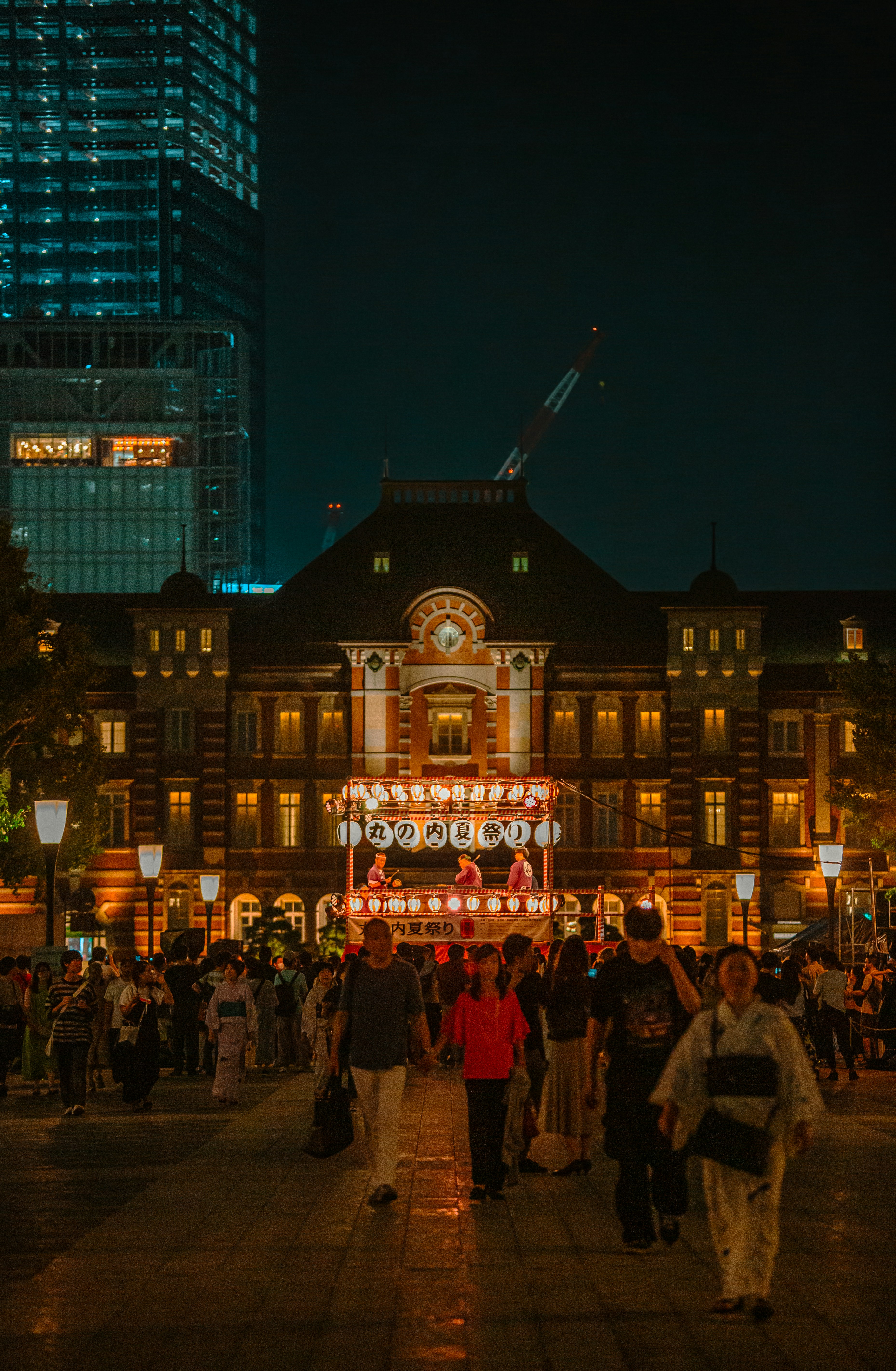 A crowd of people walking around a city at night