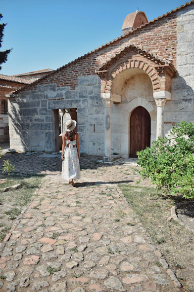 A woman in a white dress is standing in front of a building