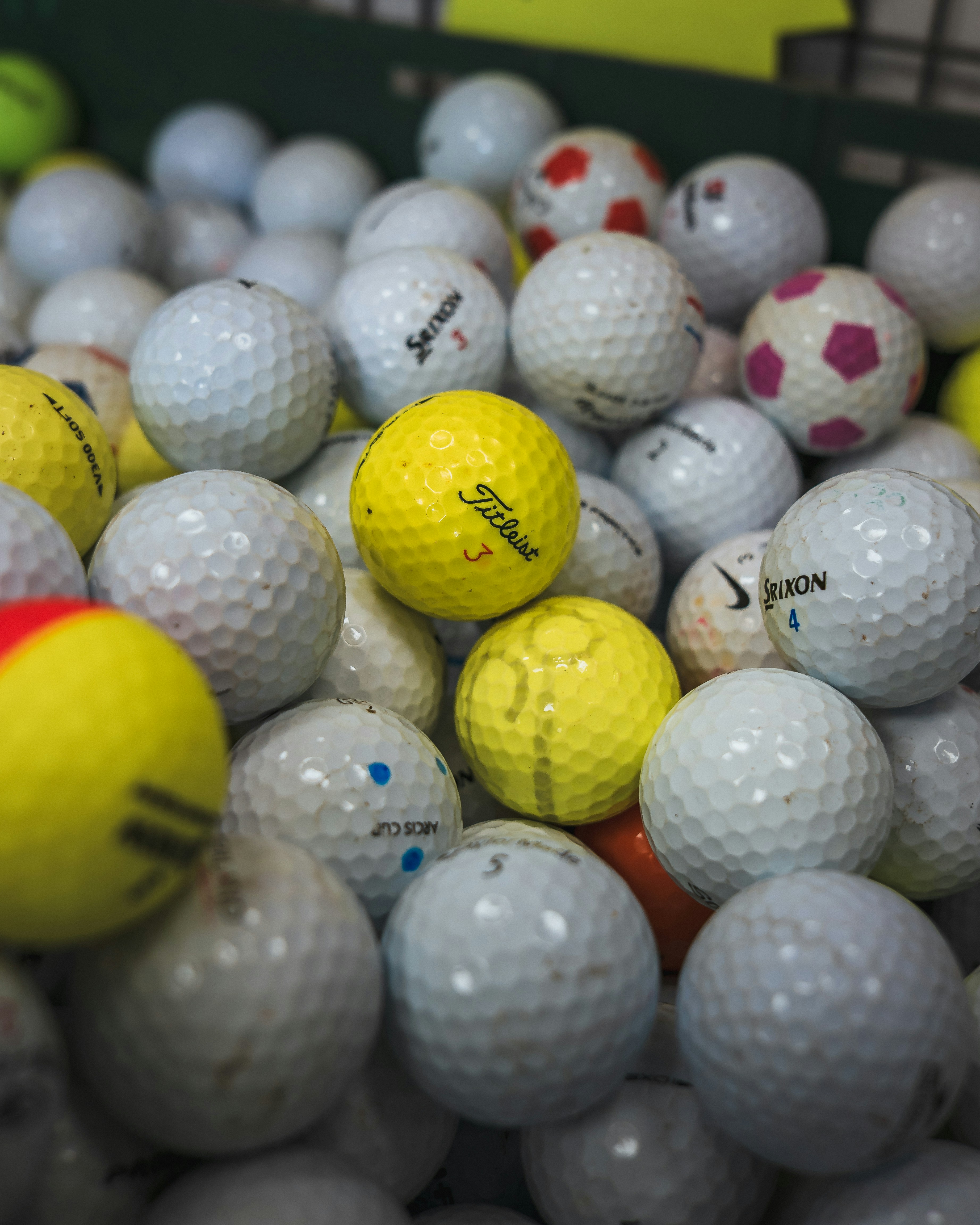 A pile of golf balls in a bin