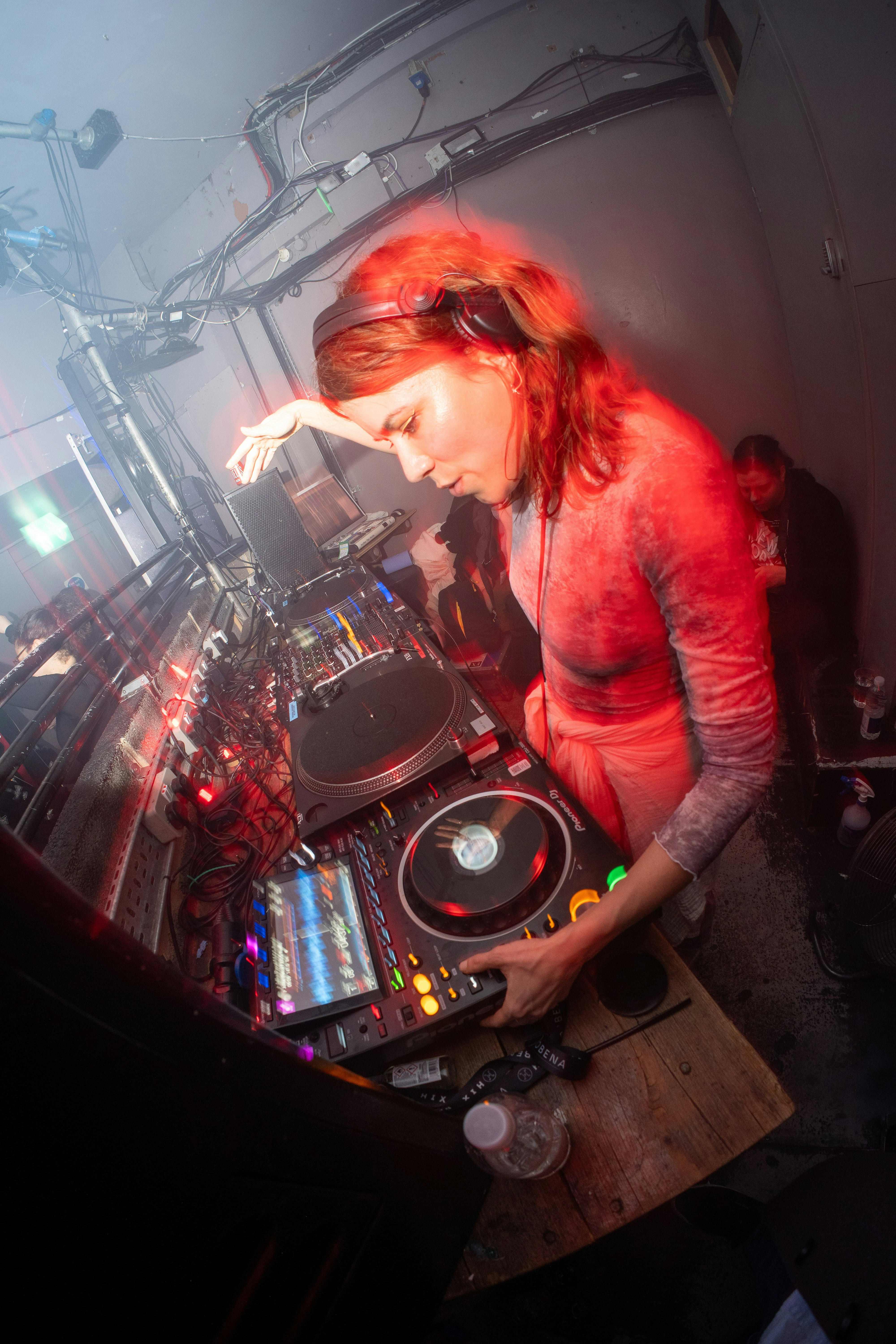 Female DJ with dark hair focused on mixing console in minimal setup