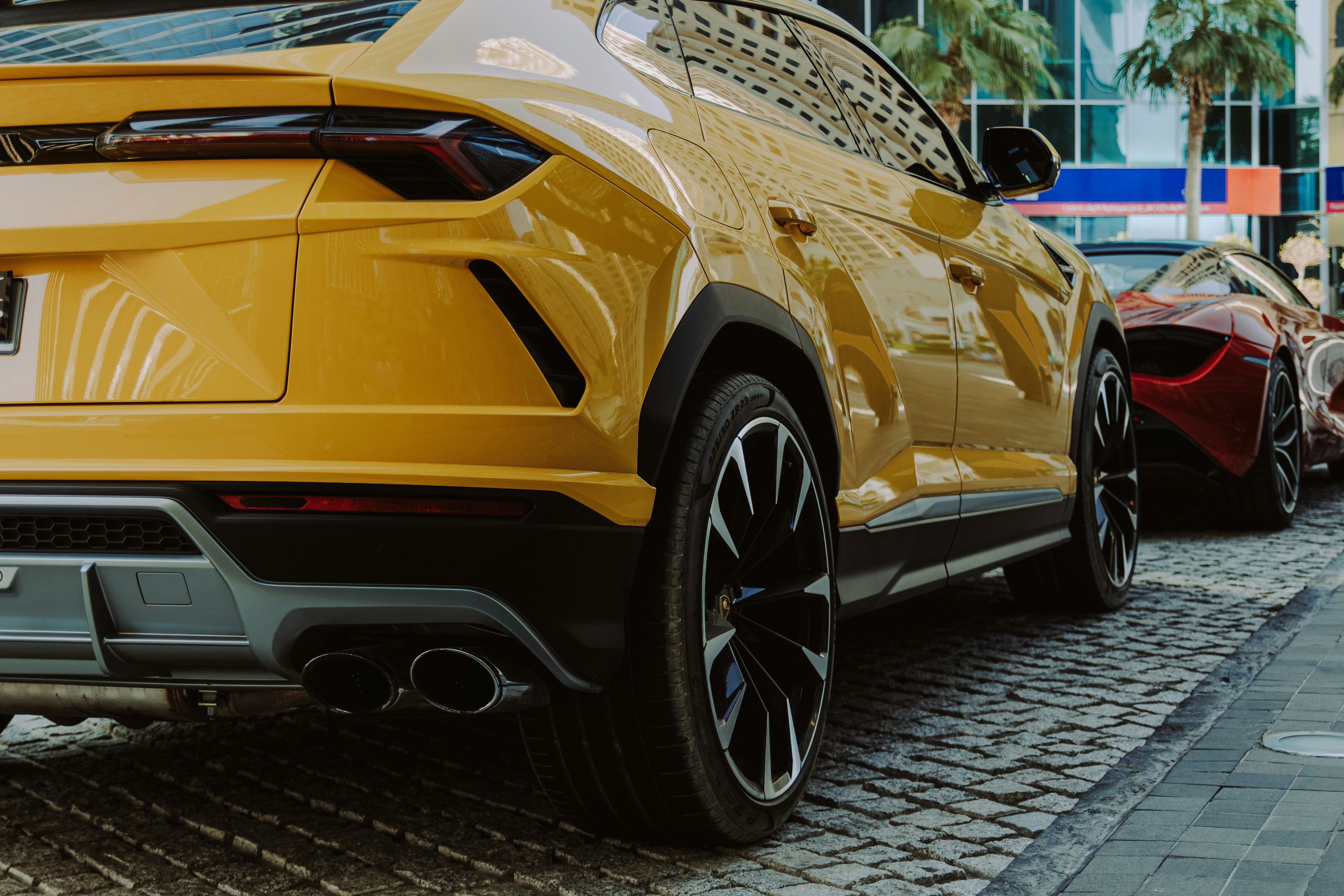 A line of cars parked on a cobblestone street, Close-up of a luxury yellow Lamborghini sports car with stylish black rims on the street