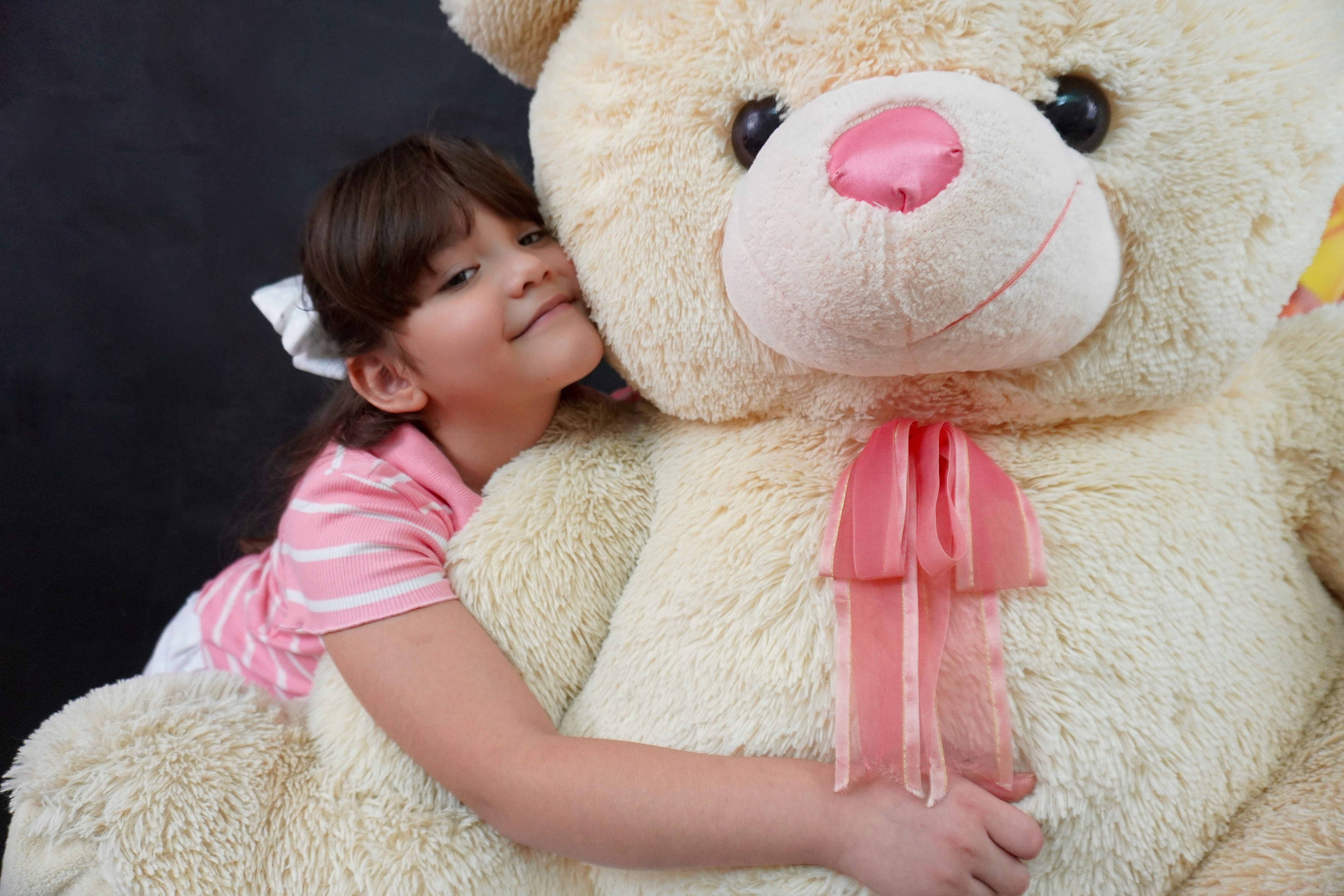 큰 테디 베어를 껴안고 있는 어린 소녀