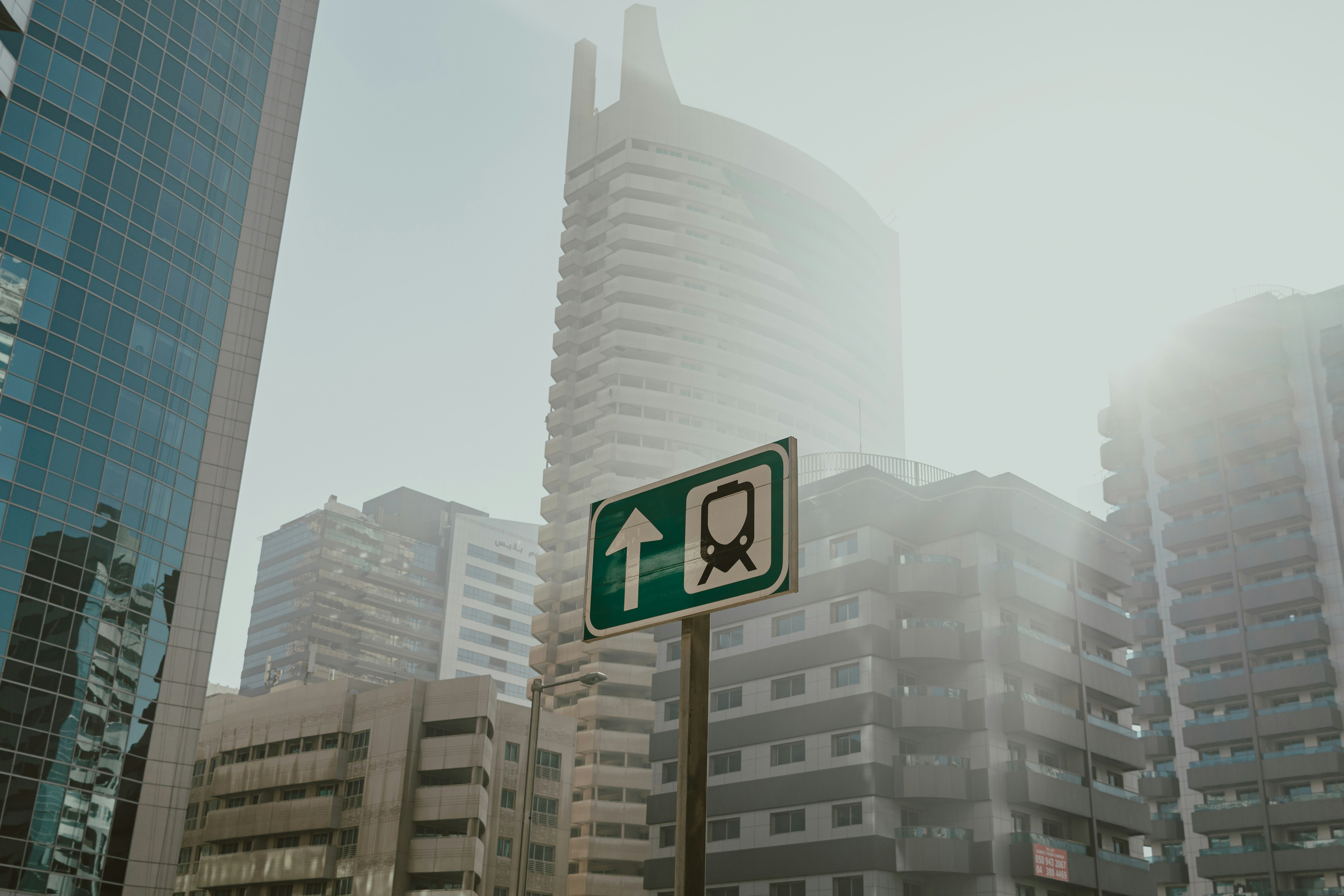 Metro sign pointing forward with modern buildings in the background