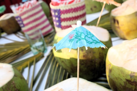 A table topped with lots of coconuts covered in umbrellas