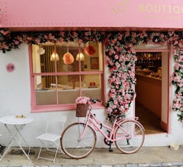 A pink bike is parked outside of a store