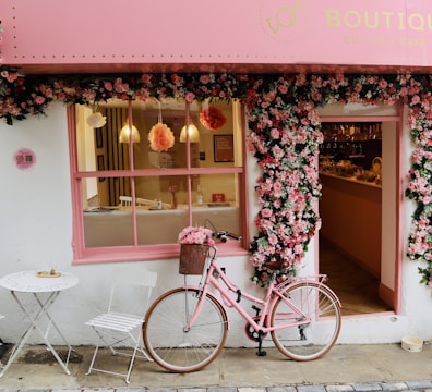 A pink bike is parked outside of a store