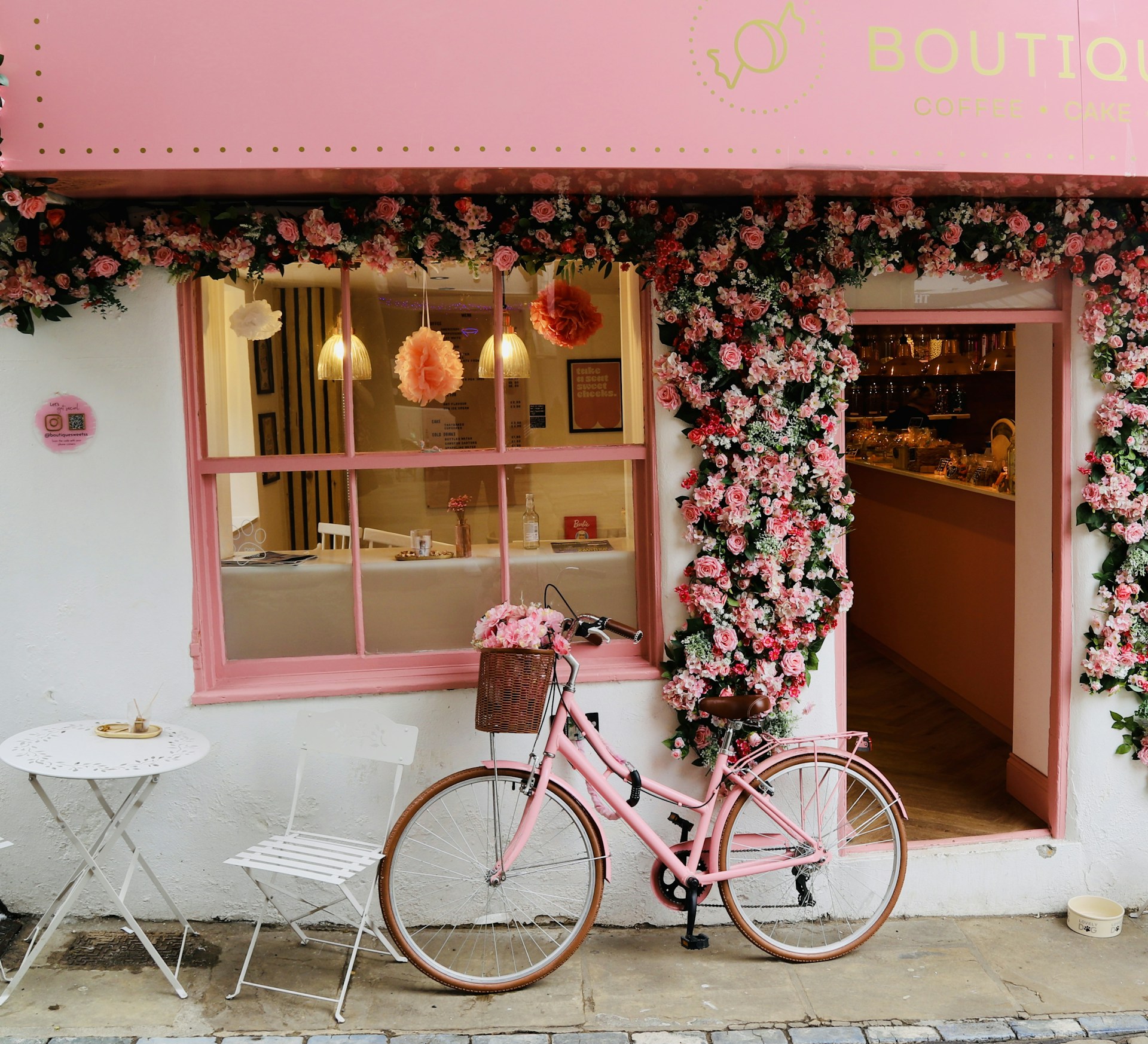 A pink bike is parked outside of a store