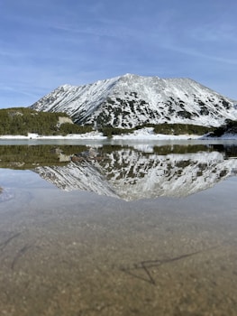 A mountain is reflected in the still water of a lake
