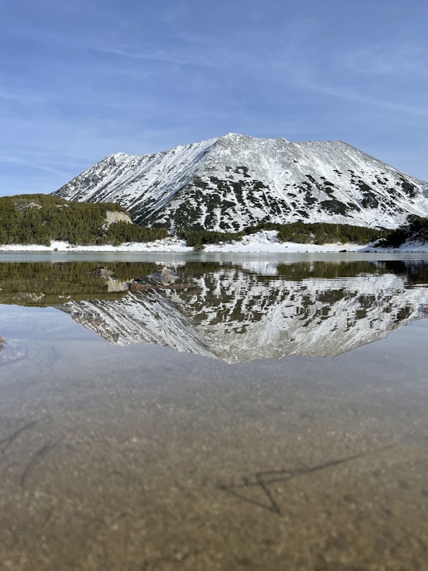 A mountain is reflected in the still water of a lake
