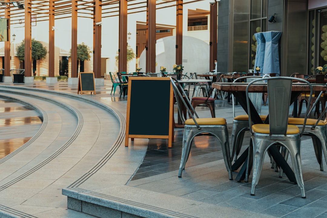A table and chairs sitting outside of a building, Curved outdoor dining area with modern seating and blank menu boards