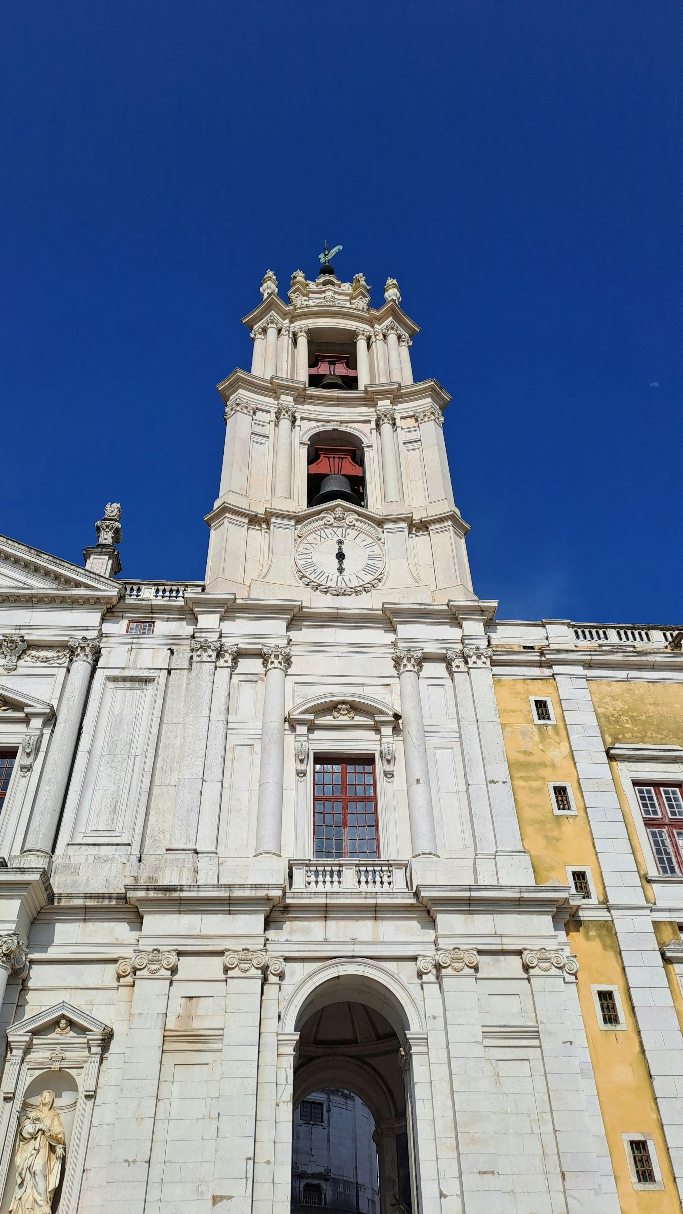Un edificio alto y blanco con un reloj a un lado