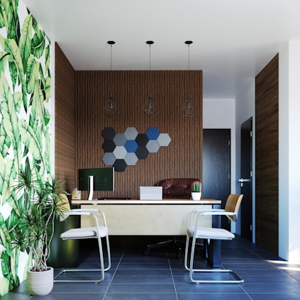 A room with a desk, chairs and a plant