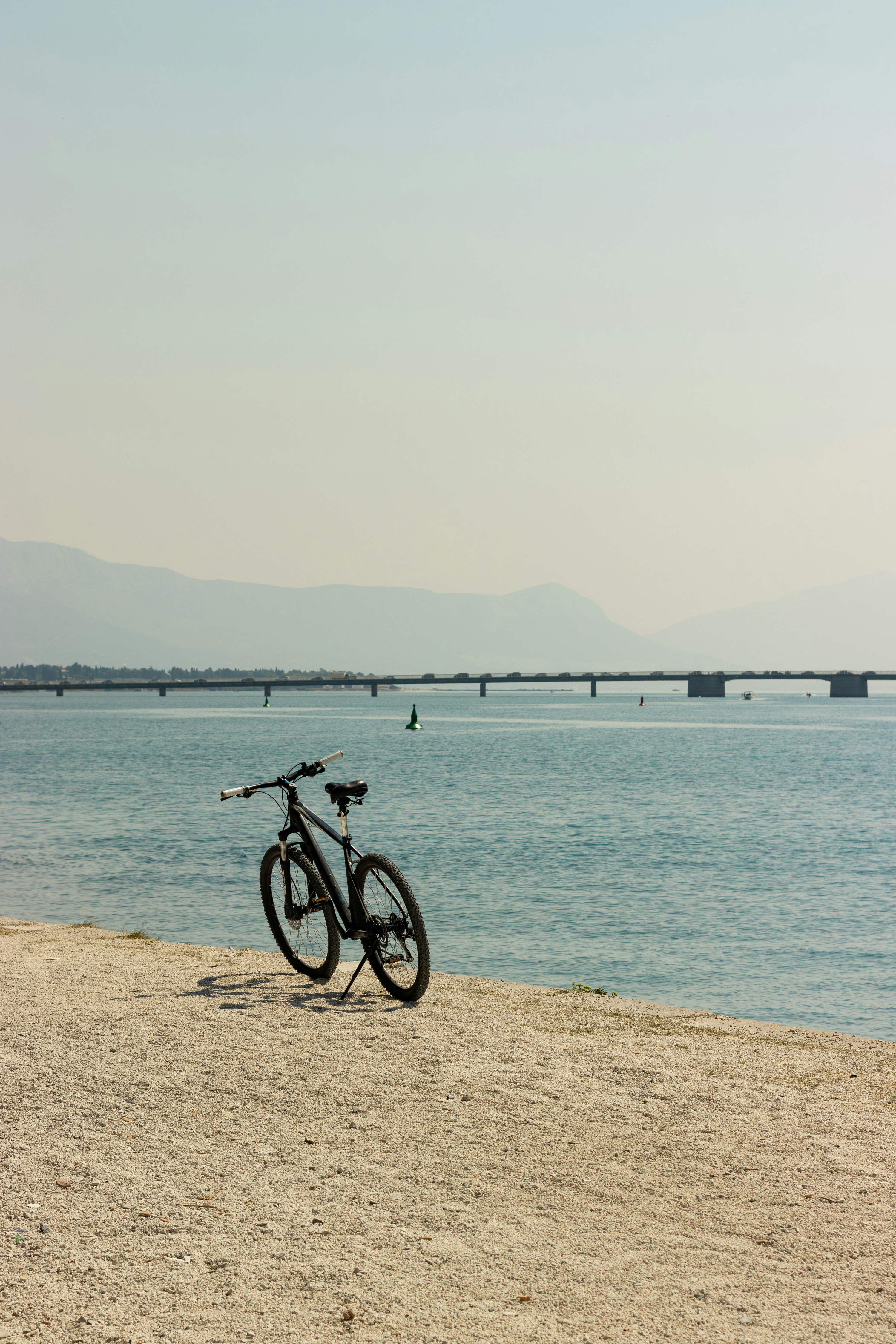 A bike is parked on the beach near the water