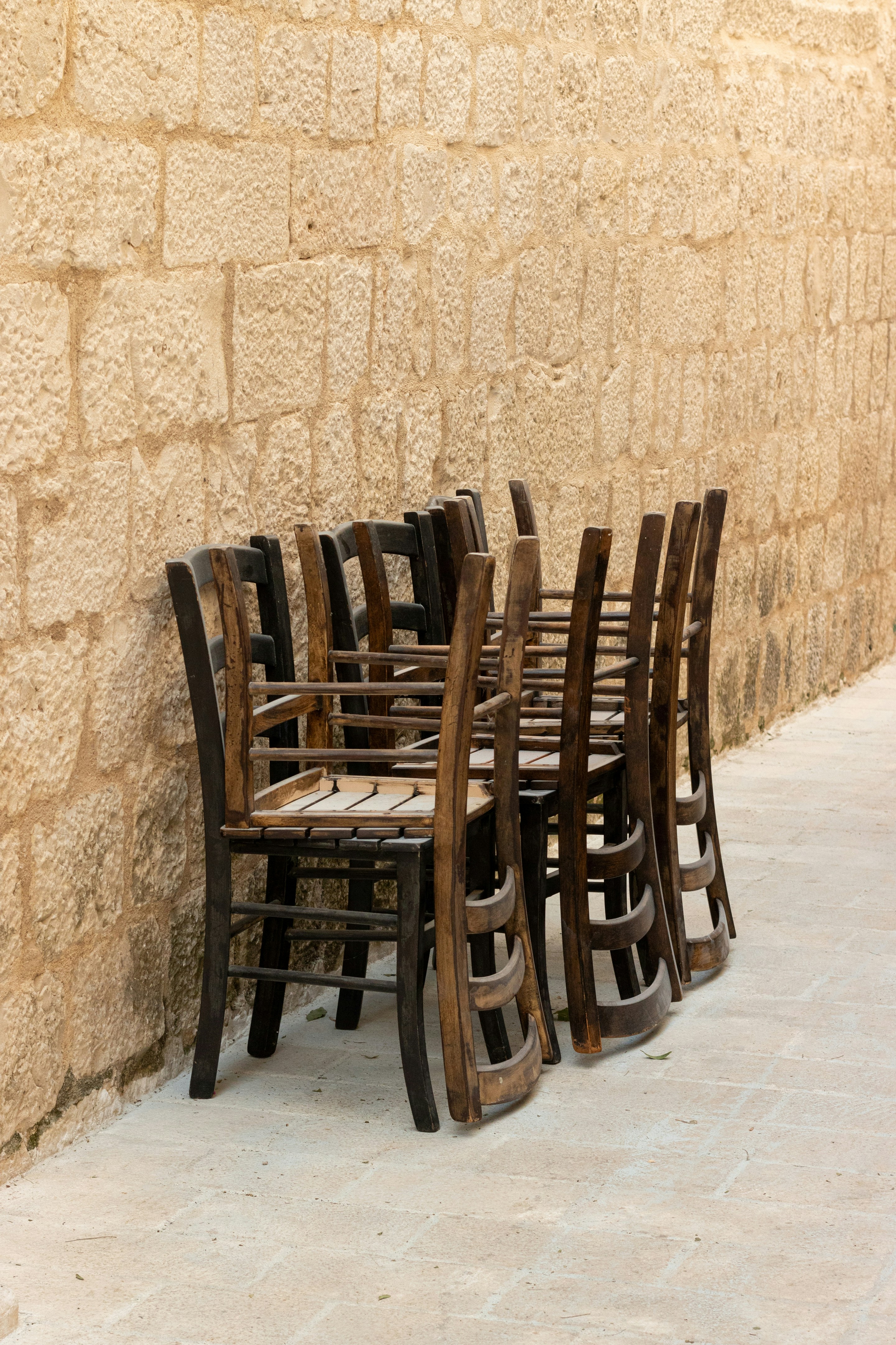 Une rangée de chaises posées à côté d’un mur de pierre
