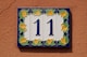 A blue and yellow house number 11 on a wall