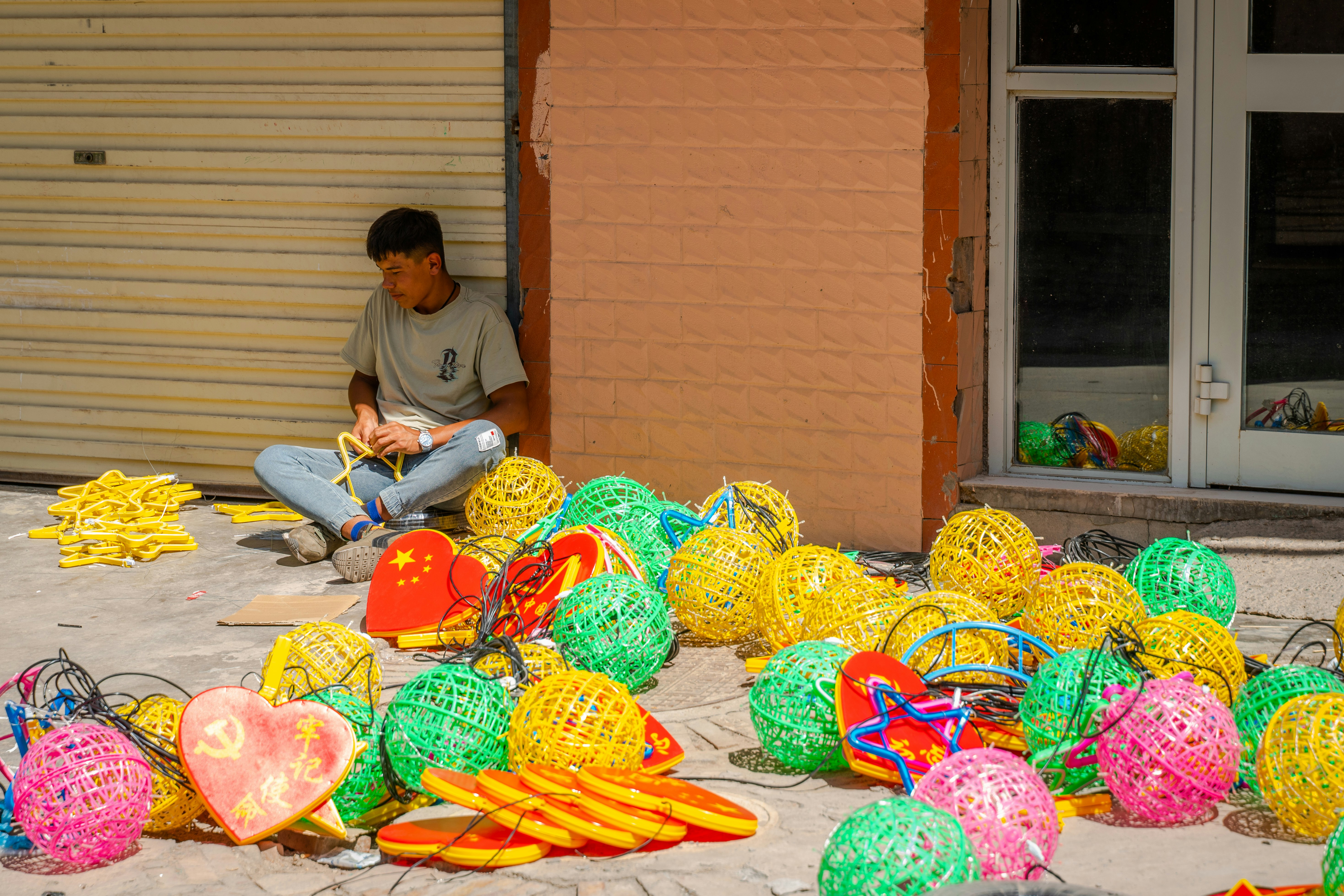 A man sitting on the ground next to a pile of balls