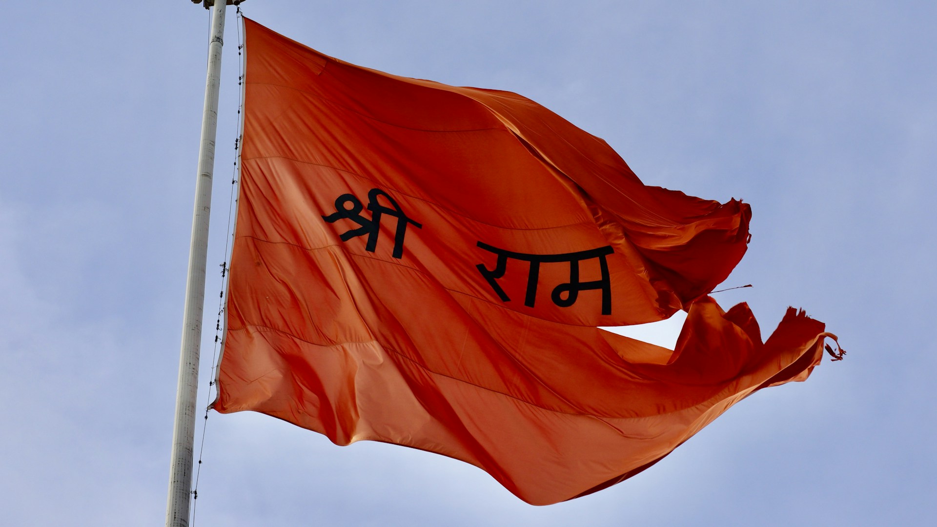 A red flag flying in the wind with a sky background