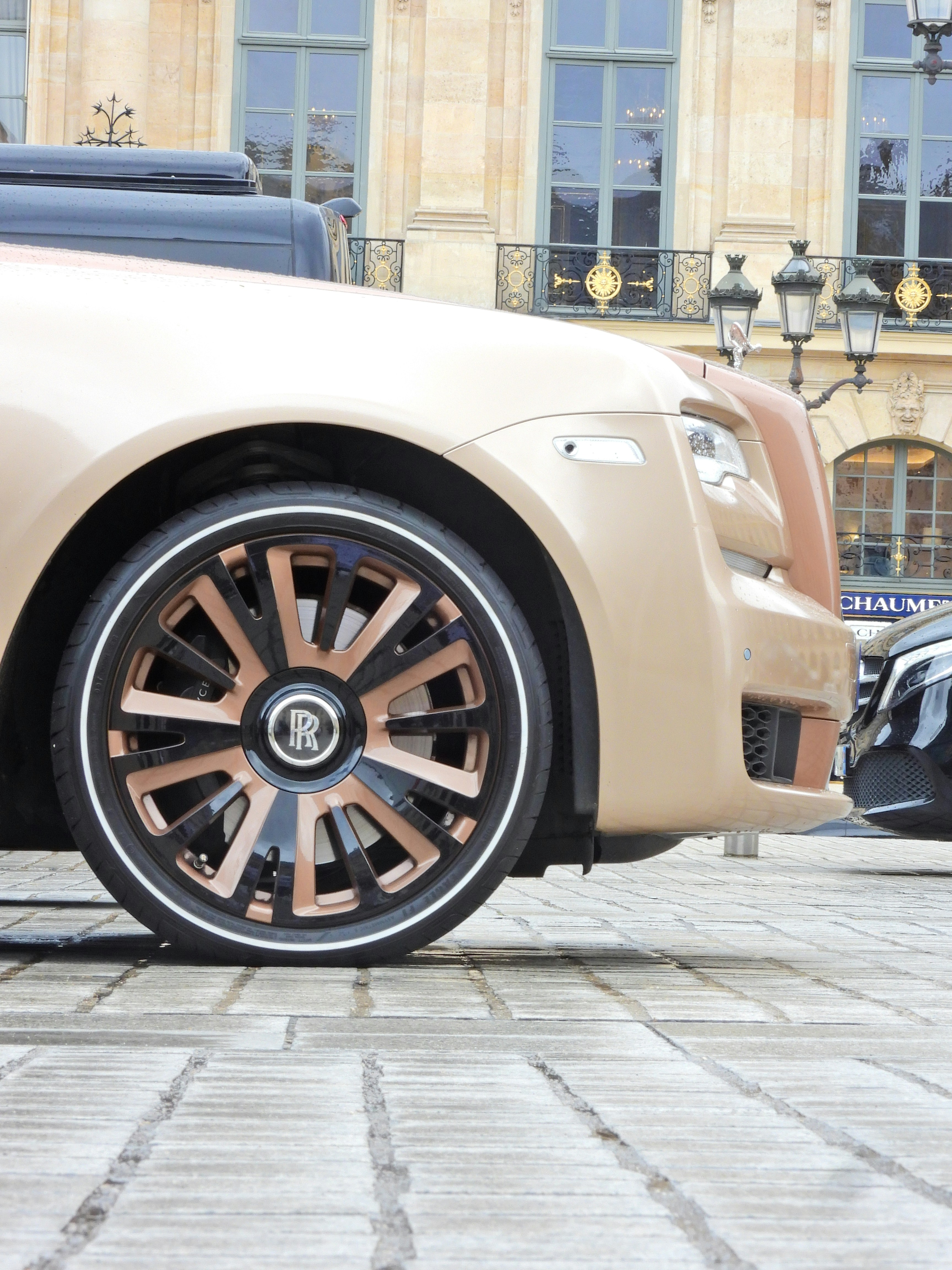 A beige rolls royce parked in front of a building