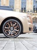 A beige rolls royce parked in front of a building