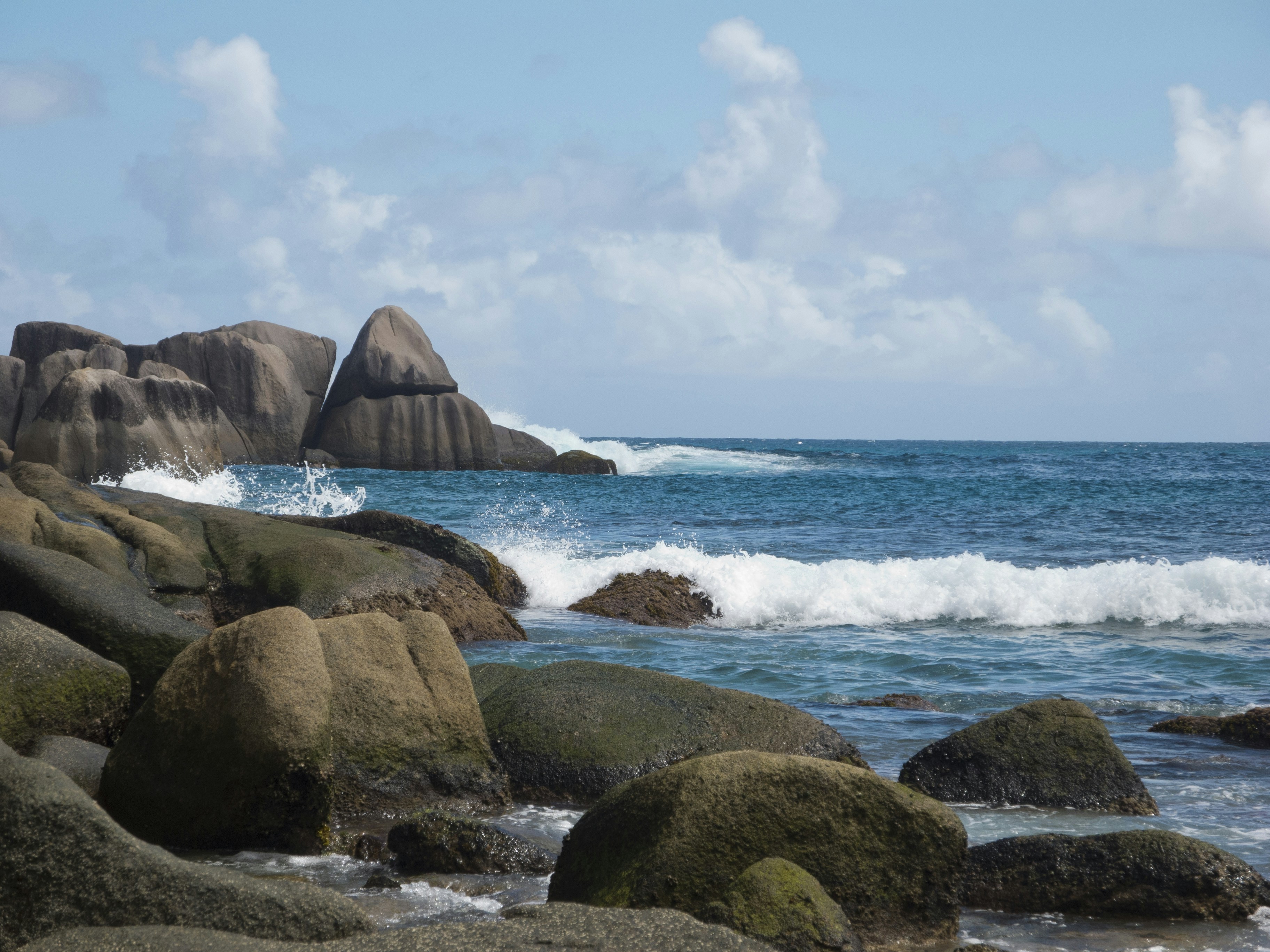 A rocky beach with waves crashing against the rocks, Playa de Seychelles.
